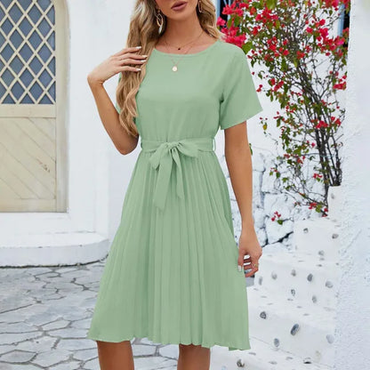 Woman wearing an elegant summer pleated dress with short sleeves and a flattering waist tie, ideal for warm-weather occasions.






