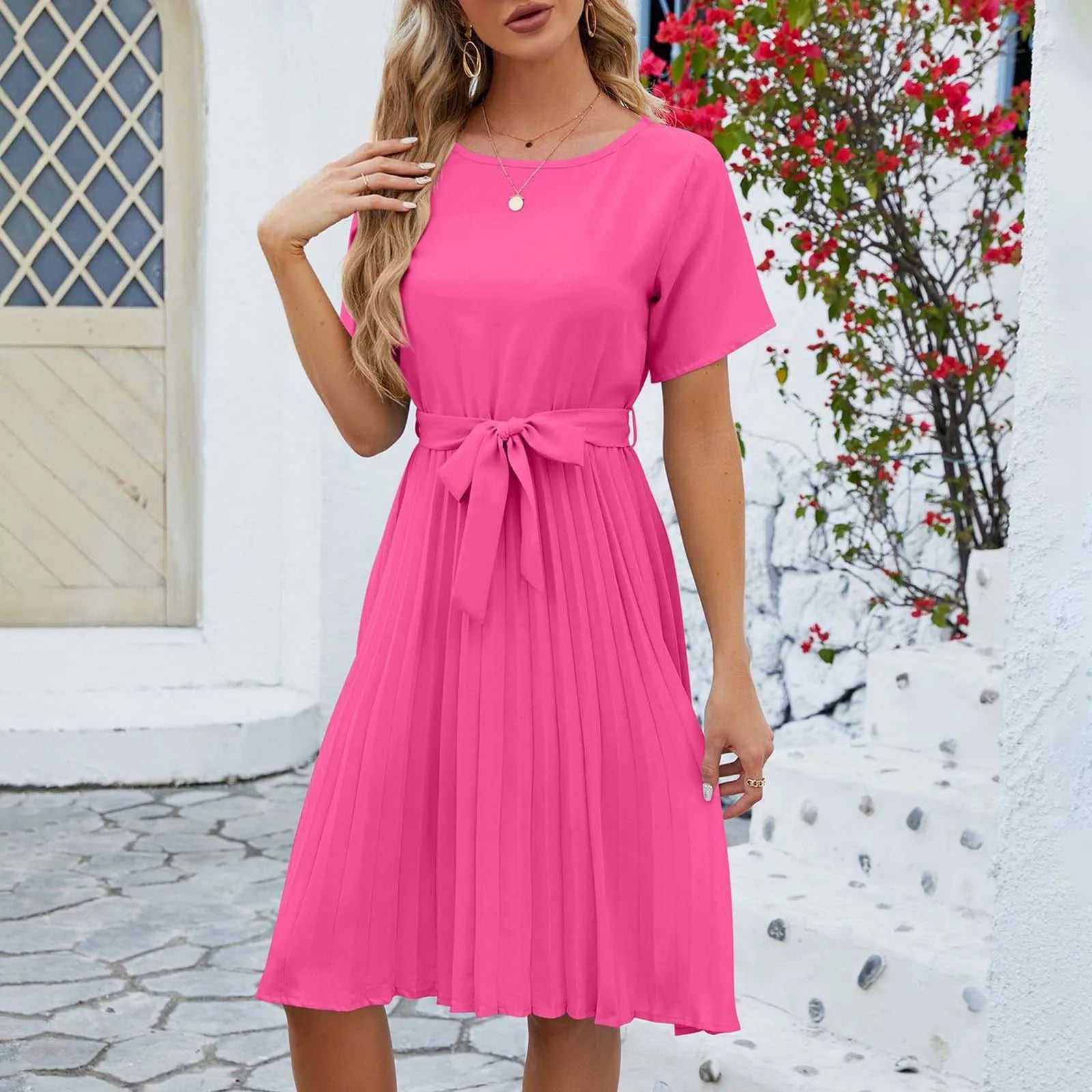 Woman wearing an elegant summer pleated dress with short sleeves and a flattering waist tie, ideal for warm-weather occasions.






