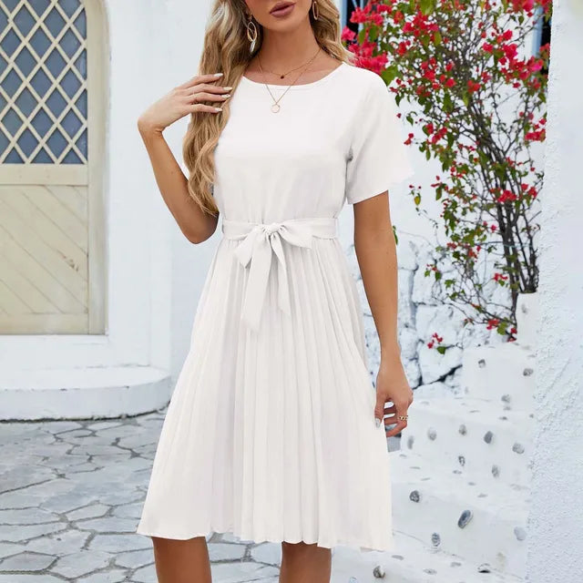 Woman wearing an elegant summer pleated dress with short sleeves and a flattering waist tie, ideal for warm-weather occasions.






